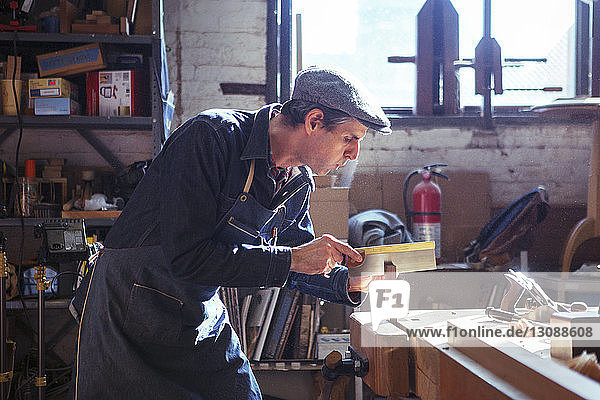 Zimmermann schneidet Holz mit der Handsäge in der Werkstatt