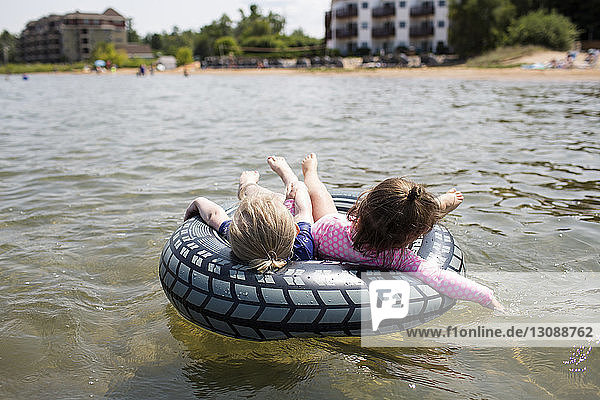 Sisters relaxing on inflatable ring in sea