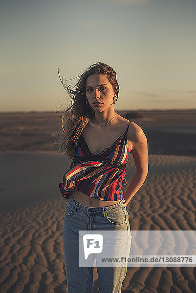 Portrait of woman standing at beach against sky during sunset
