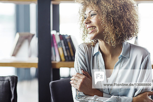 Cheerful businesswoman with arms crossed sitting at restaurant