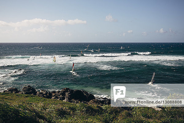 People windsurfing on sea against sky