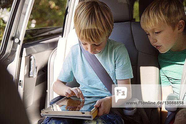 Junge benutzt Tablet-Computer  während er im Auto sitzt