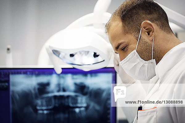 Männlicher Zahnarzt stellt Lampe gegen Röntgenstrahlen in der Klinik