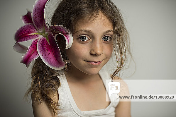 Portrait of confident girl wearing lily against wall at home