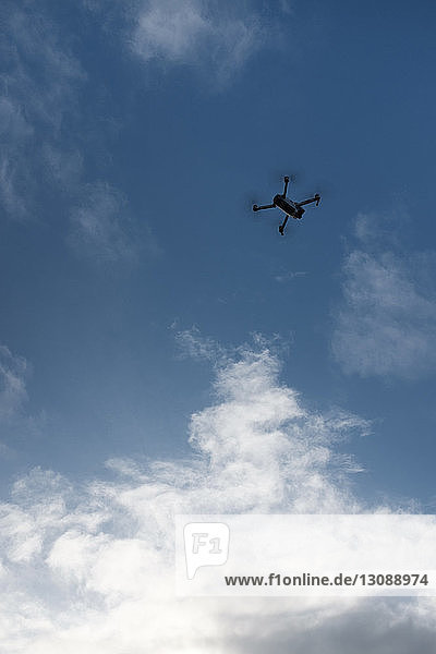 Tiefwinkelansicht einer Drohne  die gegen bewölkten Himmel fliegt