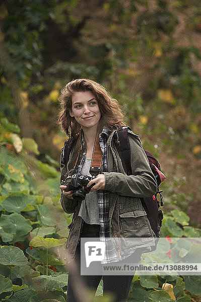 Lächelnde Wanderin mit Kamera im Wald