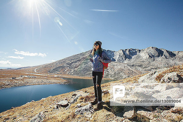 Happy woman standing at mountain against clear sky on sunny day