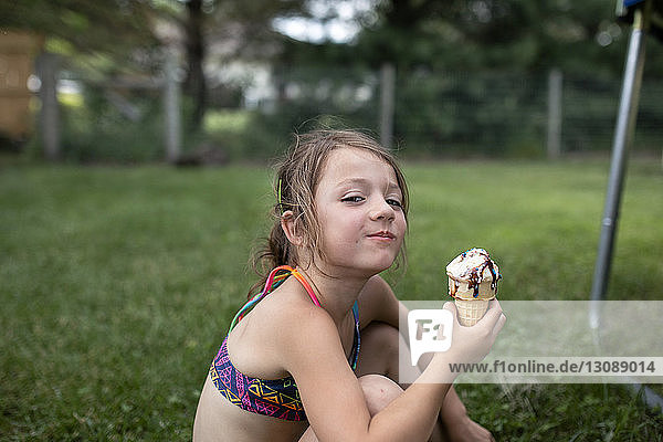 Porträt eines Mädchens  das im Hof sitzend eine Eistüte hält