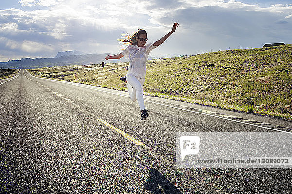 Frontansicht einer Frau  die an einem sonnigen Tag auf Straße und Feld springt