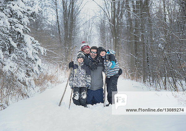 Portrait of father with sons on snowy field against bare trees