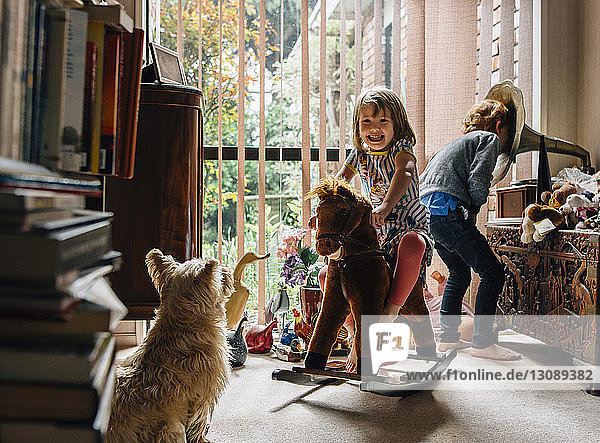 Glückliche Geschwister spielen zu Hause mit Hund im Vordergrund