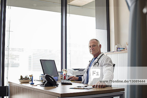 Portrait of doctor working at desk by window in hospital