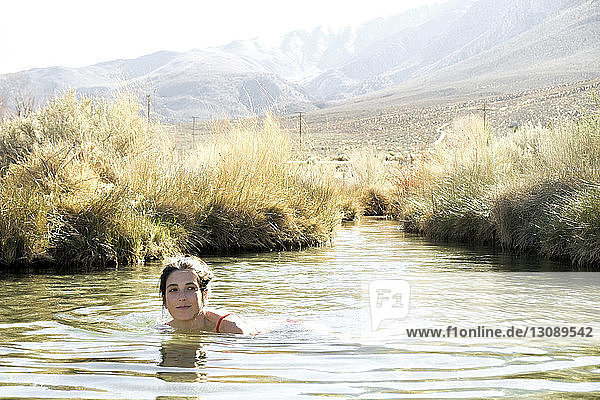 Woman swimming in lake against mountain
