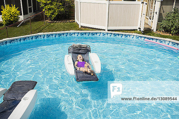 Happy girl relaxing on inflatable raft in swimming pool