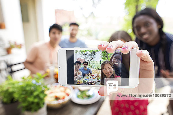 Multi-ethnic friends taking selfie at outdoor lunch table