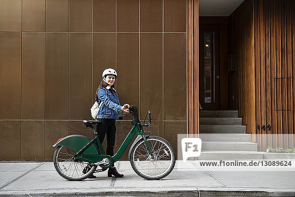 Frau mit Fahrrad auf Gehsteig am Gebäude
