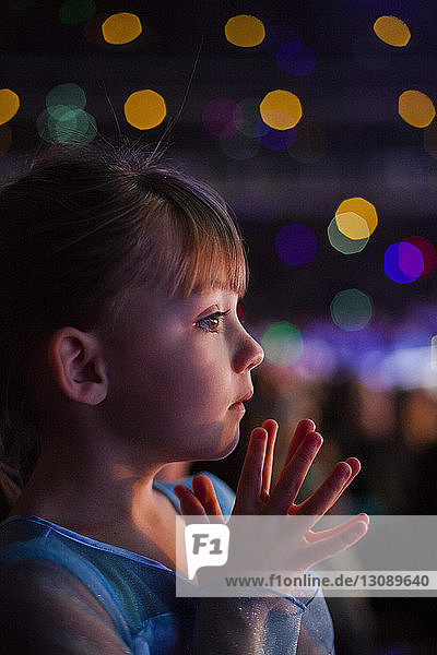 Close-up of thoughtful girl against defocused lights at night