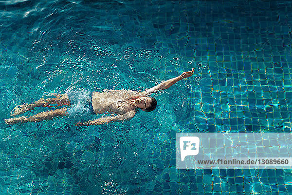 Hochwinkelansicht eines Mannes ohne Hemd  der im Schwimmbad des Ferienorts schwimmt