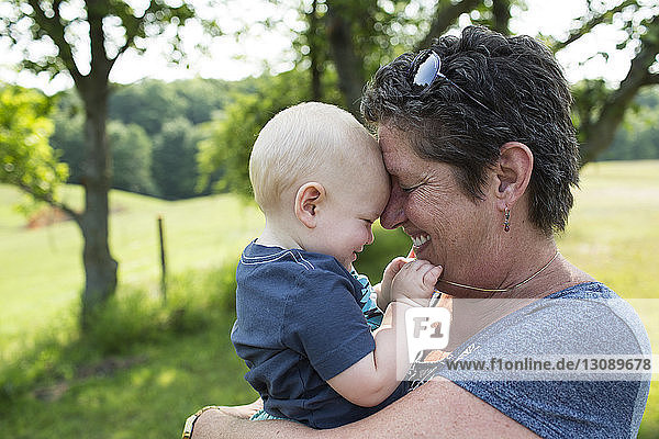 Close-up of grandmother carrying grandson while standing on field in park
