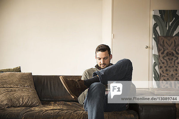 Smiling businessman sitting on sofa against wall in creative office