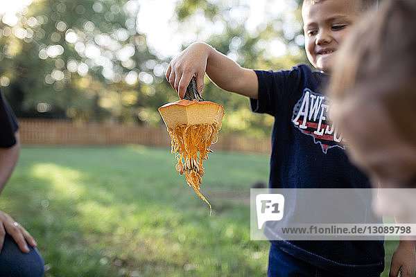 Junge hält Kürbisstengel  während er an Halloween im Hof steht