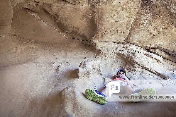 Boy lying on rock in cave