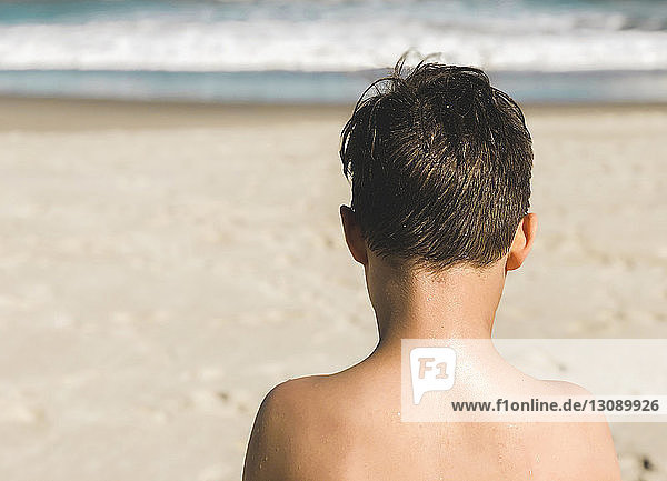 Rückansicht eines Jungen ohne Hemd am Strand im Sommer