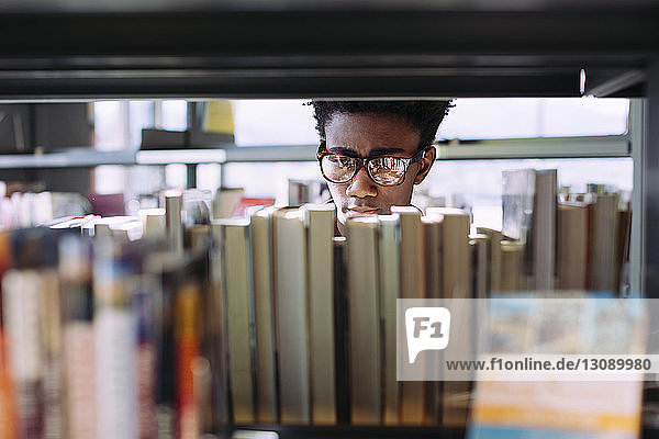 Man searching books in shelf at library
