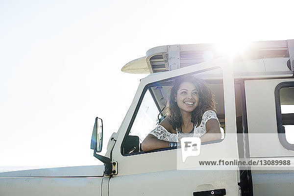 Happy woman looking through car window during sunny day