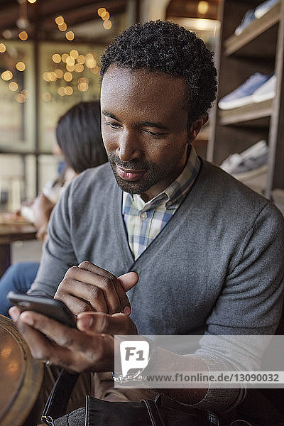 Junger Mann verschickt Textnachrichten  während er im Café sitzt