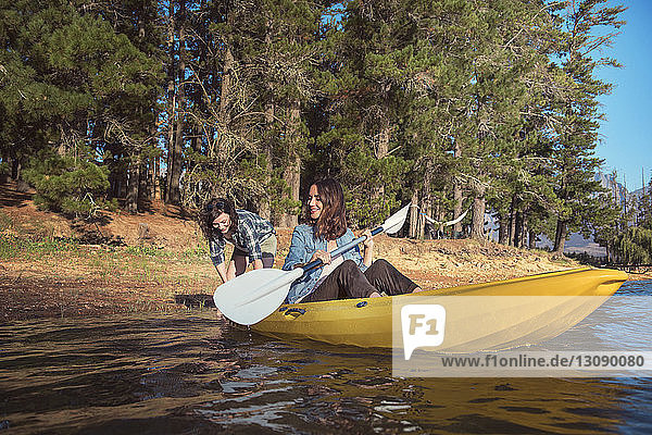 Happy female friends with kayak on lake
