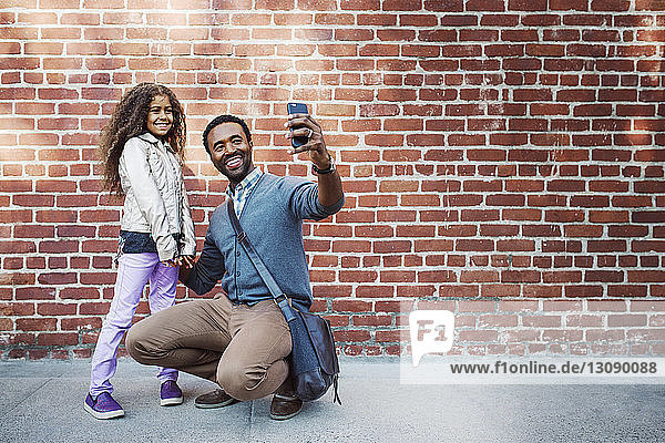 Glückliche Vater und Tochter nehmen Selbstliebe am Smartphone