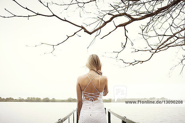 Junge Frau in weißem Kleid auf einem Dock