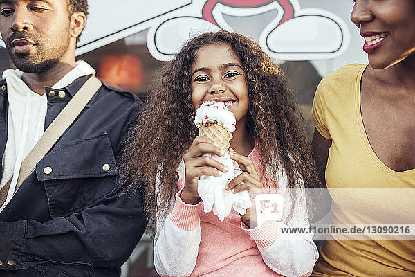 Porträt eines Mädchens  das Eiswaffeln hält  während es mit den Eltern zusammensitzt