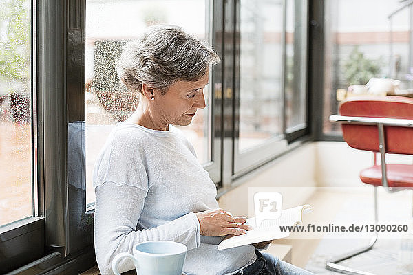 Side view of mature woman reading book at home