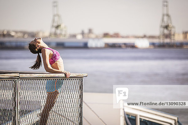 Seitenansicht einer Frau  die an einem Geländer gegen einen Fluss in der Stadt steht