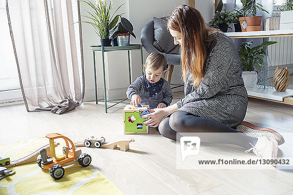 Mutter und Sohn spielen mit Spielzeug  während sie zu Hause auf dem Boden sitzen
