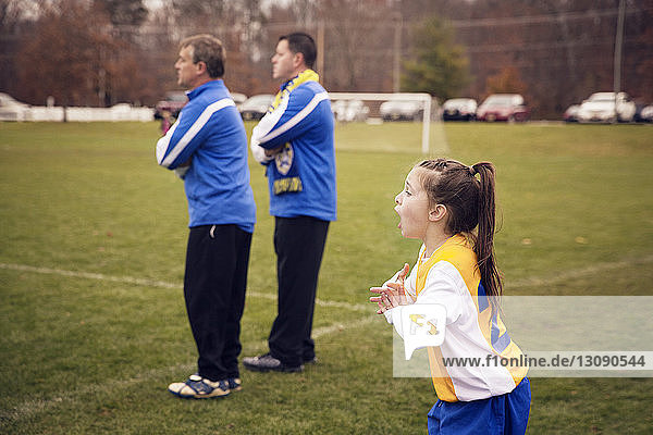 Excited soccer player and trainers standing on playing field