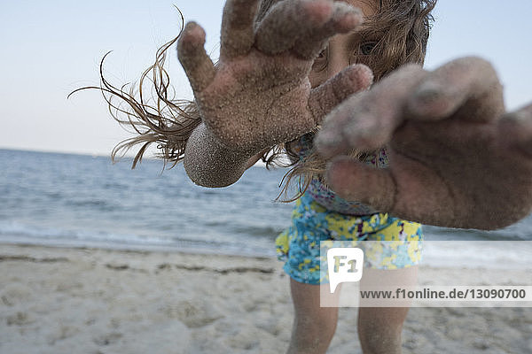 Porträt eines Mädchens mit unordentlichen Händen  das am Strand vor klarem Himmel steht