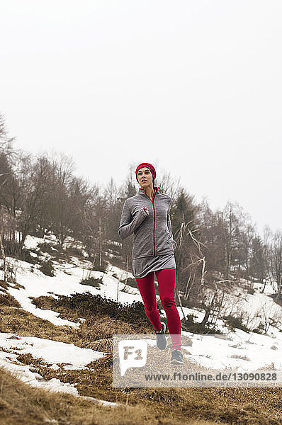 Determined female athlete running on mountain during winter