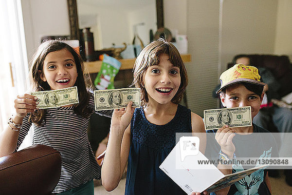 Porträt glücklicher Geschwister zeigt US-Papiergeld zu Hause