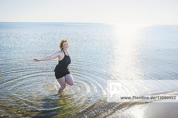 High angle view of carefree woman in sea on shore against clear sky