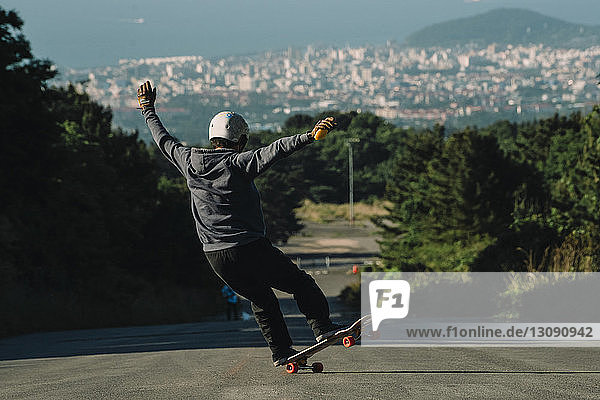 Rückansicht eines Mannes beim Skateboarden auf der Straße gegen das Stadtbild