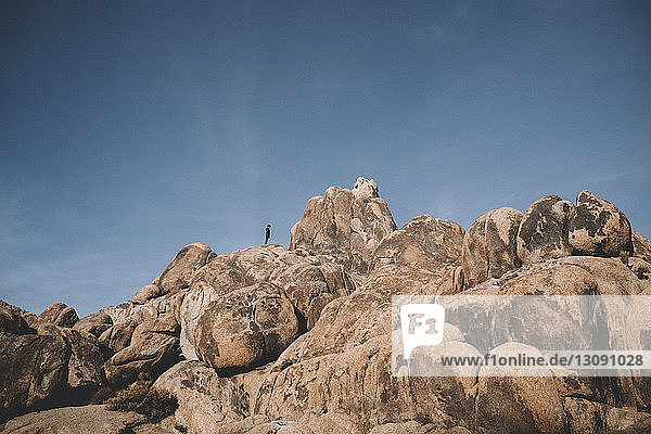 Distant view of boy on rock formations against sky at desert