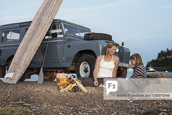 Mother and daughter sitting by campfire