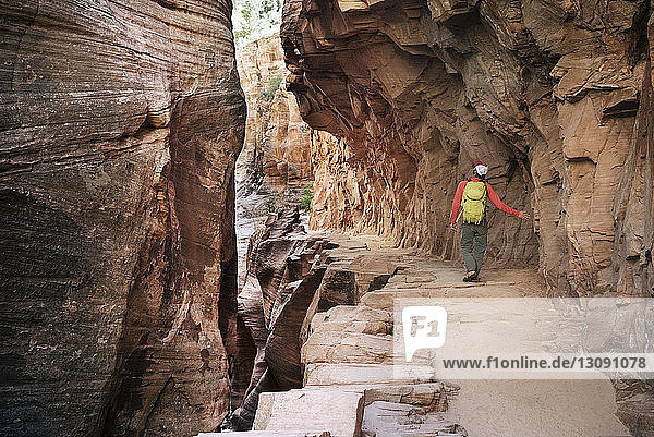 Rückansicht eines männlichen Wanderers  der in einer Höhle im Zion-Nationalpark wandert