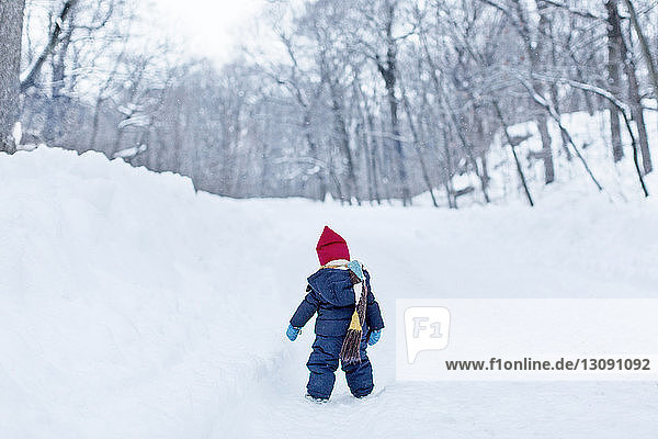 Rear view of baby girl standing on snow covered field
