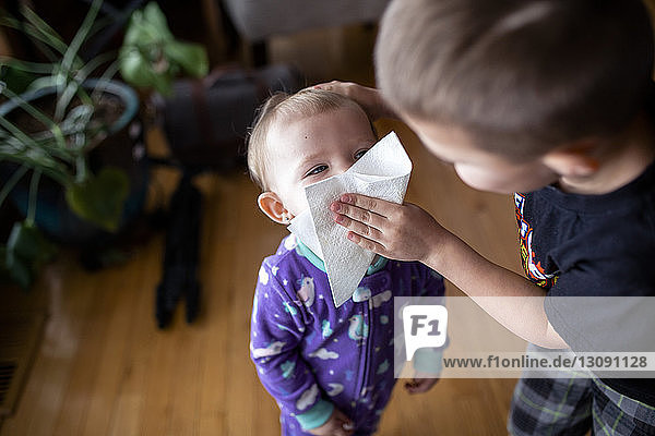 Bother wiping sister's face with facial tissue at home