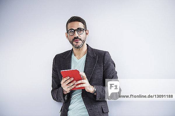 Portrait of businessman holding digital tablet and standing in creative office
