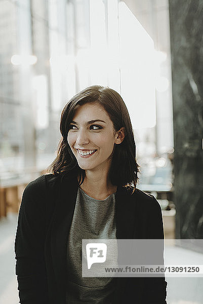 Lächelnde Frau schaut weg  während sie im Cafe steht
